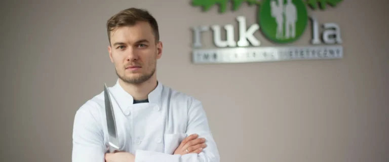 Dietetyk Dawid Białowąs stojący przy ścianie